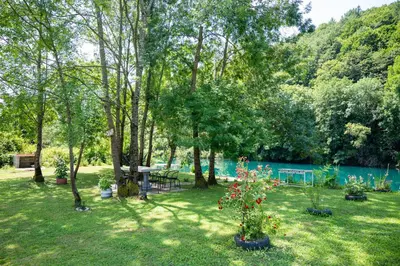 a yard with a picnic table and trees and a lake at Apartman Kestenovac in Orašac