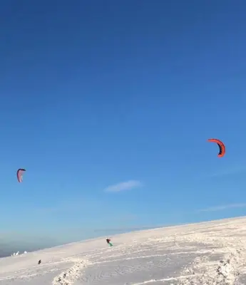 two people are flying kites on the beach at Kupres, centar, apartman in Kupres