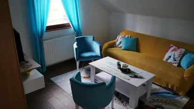 a living room with a yellow couch and blue chairs at Kuća za Odmor Naša Priča in Šipovo