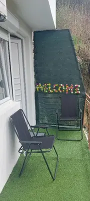 a chair on a balcony with a table and flowers at Apartman Heli Meli 2 in Jajce