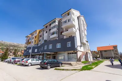 a large building with cars parked in a parking lot at Apartman Krželj A1 in Livno