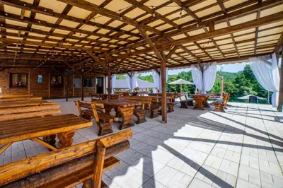 a pavilion with wooden benches and tables and umbrellas at Una Relax in Bosanski Novi