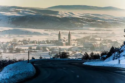 a snow covered road with a city in the distance at Apartment Kupres in Kupres