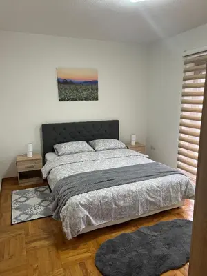 a bedroom with a large bed and two rugs at Teal Apartment 2 in Bihać