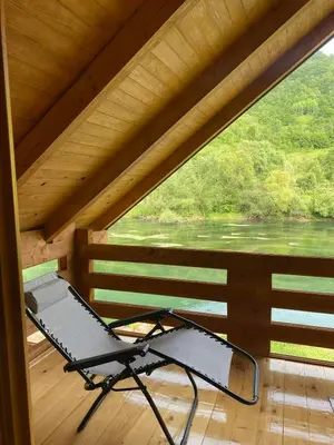 a chair on a porch with a view of a river at Vikendica Ana in Šipovo