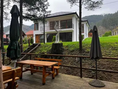 a house with a picnic table and two umbrellas at Villa Bella Una-Apartman in Ostrožac