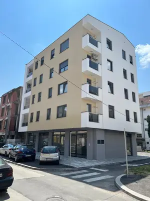 a building with cars parked in a parking lot at Apartmani Kastel 1 in Banja Luka