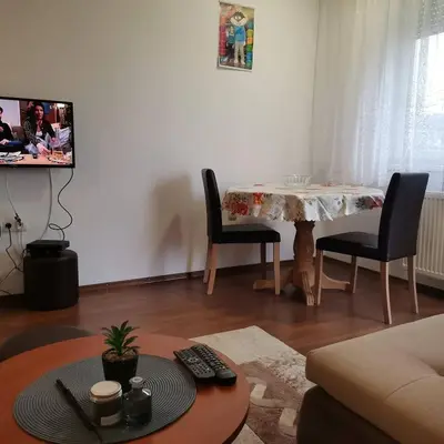 a living room with a table and chairs and a tv at Stan na dan Banja Luka in Banja Luka