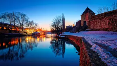 a river with snow on the ground next to a building at Apartmani Kastel 4 in Hiseti
