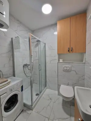 a bathroom with a washing machine and a sink at Apartmani Stan na dan 34 in Banja Luka