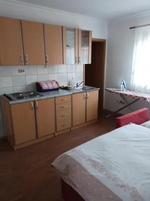 a kitchen with wooden cabinets and a sink and a bed at studio SM IK 3 in Tomislavgrad