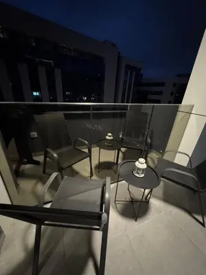 three chairs and tables on a balcony at night at Apartman AK IX in Banja Luka