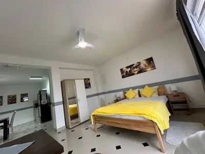 a bedroom with a bed with a yellow blanket at Studio Apartman Orhideja in Sanski most