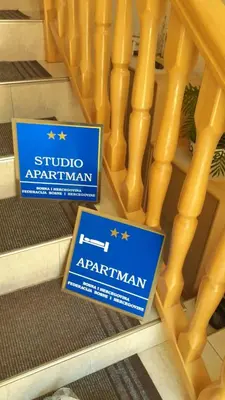two signs sitting on the floor next to a wooden staircase at Apartmani Orhideja za 2 osobe studio in Sanski most