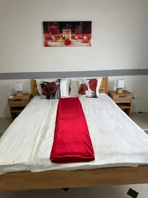 a large white bed with a red blanket on it at Apartmani Orhideja za 4 osobe in Sanski most