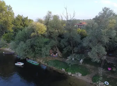 a group of people sitting on the shore of a river at Apartmani Una Lux2 in Spilja