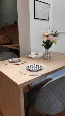 two plates on a wooden table with a vase of flowers at Apartment Lena 51 in Banja Luka
