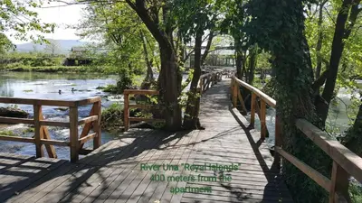 a wooden bridge over a river with trees and water at Apartman EM-Bajkeraj in Bihać