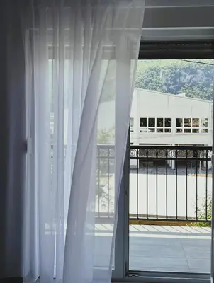 a window with white curtains and a view of a building at Guest House 369 in Jajce
