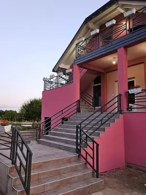 a pink building with stairs in front of it at Apartments Una Roots in Orašac