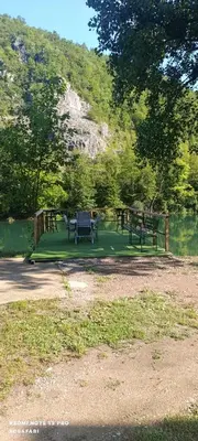 a picnic table and benches in a park next to a lake at Holiday home una in Bosanska Krupa