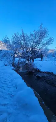 a snow covered field with trees and a river at Golden Spa A-Frame 1 in Bihać