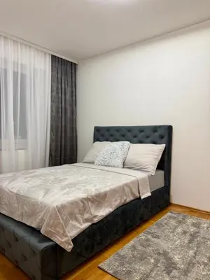 a bedroom with a bed with a black headboard and a window at Alexa Apartmani in Banja Luka