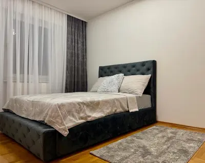 a bedroom with a black bed with a window at Apartmani Alexa in Banja Luka
