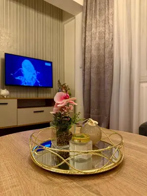 a table with a glass tray with flowers and a television at Apartmani Alexa in Banja Luka