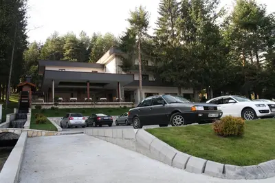 a group of cars parked in front of a house at Hotel Balkana Vidović in Mrkonjić Grad