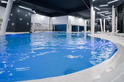 a large pool with blue water in a building at Sound apartment in Fojnica