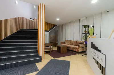 a lobby with a staircase with a couch and a chair at Kašmir in Bugojno