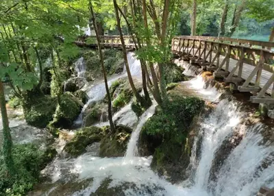 a river with a bridge over a waterfall at Apartman D&D 2 in Jajce