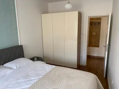 a bedroom with a white bed and a cabinet at Zeus Apartment in Banja Luka